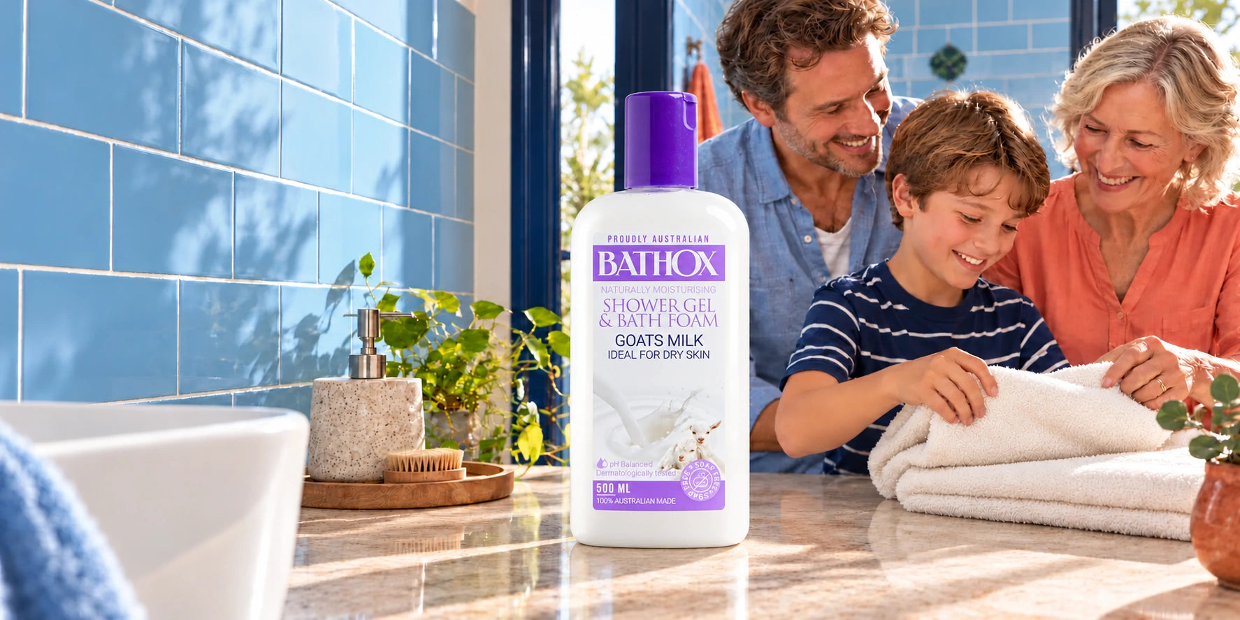 Goat’s Milk beside a family sharing a towel-folding moment in a blue bathroom.