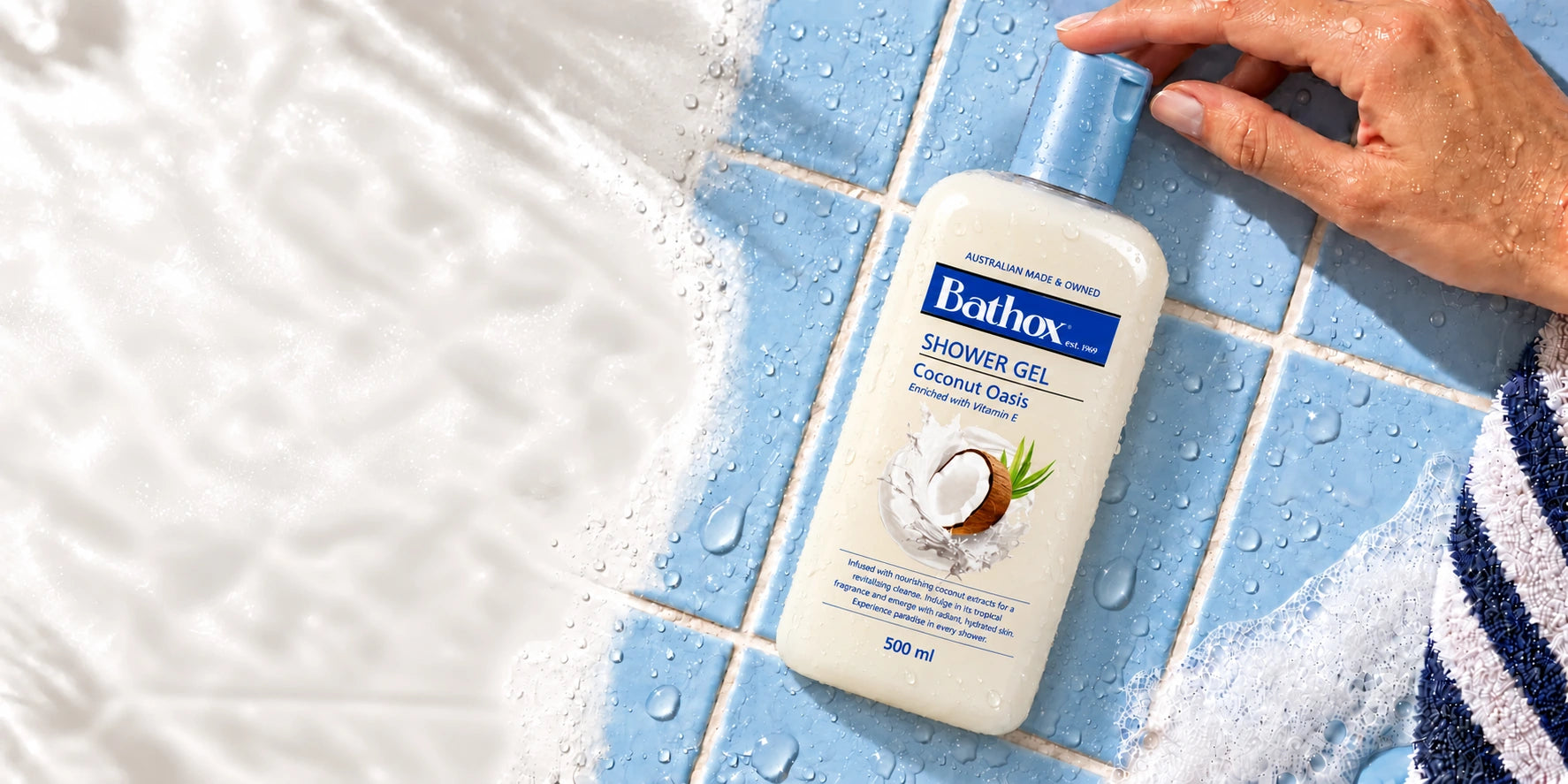 Bathox Coconut Oasis on pale blue tiles, with a hand resting on the cap.
